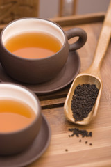 Tea serving in brown cups with teapot and wooden cutlery