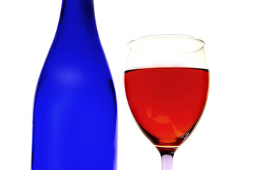 glass of red wine and blue bottle, on white
