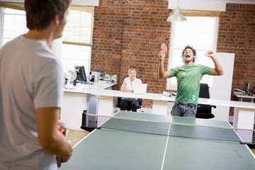 Two men in office space playing ping pong - obrazy, fototapety, plakaty