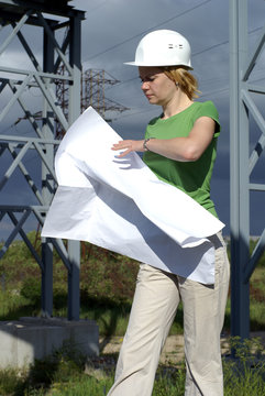 Woman engineer or architect with white safety hat, drawings and