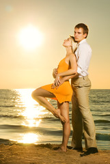 Young couple in love near the ocean at sunset