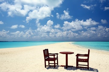 Fototapeta na wymiar Dwa krzesła i jeden tabeli są na plaży