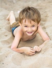 Happy child sunbathes on a beach