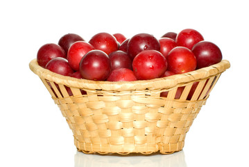 Wicker basket with cherry plums isolated on the white background