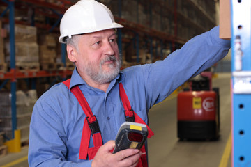 Senior worker with bar code reader at the shelf