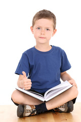 6-7 years old boy sitting with book isolated on white