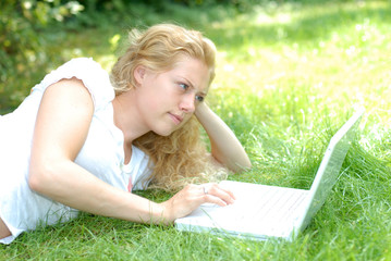 Frau mit Laptop auf Wiese