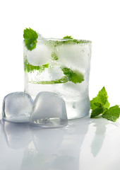 glass of ice water with fresh mint, on white