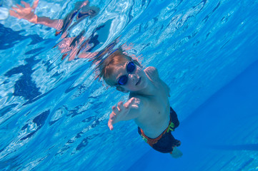 Boy swimming underwater, sunny outdoor conditions
