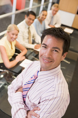 Businessman with four businesspeople at boardroom table in backg