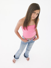 Fototapeta premium Young girl standing with hands in pockets frowning