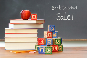 Pile of books with wooden blocks in front of chalkboard