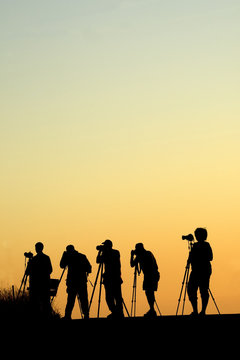 Silouette of five photographers lined up shooting photos