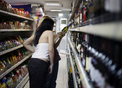 Two Girls Choose A Wine In A Supermarket