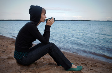 Pretty girl with cup near sea