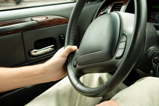 man driving a car, holding steering wheel