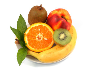 Orange, peach, banana in a white plate on light background.