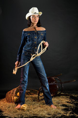 Naklejka premium Young attractive brunette in cowboy hat and jeans suit