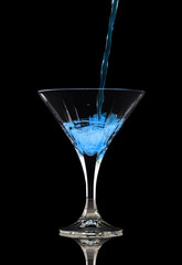 Closeup of pouring a blue cocktail into glass
