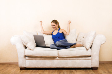 Fototapeta na wymiar young woman on a lounge with laptop is cheering