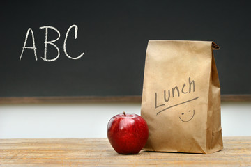 Paper lunch bag on desk with apple