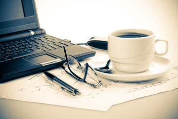 Pen, chart, notebook, eyeglasses and cup of coffee.