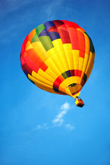Multicoloured balloon flying in the clean blue sky.