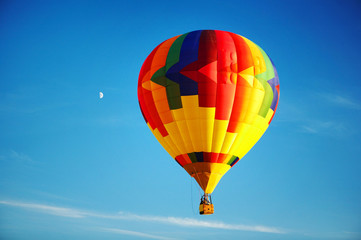 Multicoloured balloon flying in the clean blue sky.
