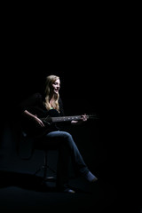 Fototapeta premium woman on dark stage performing with the guitar