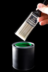 A clean paint brush about to be dipped into a can of green paint