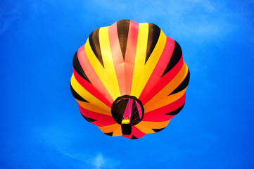 Multicoloured balloon flying in the clean blue sky.