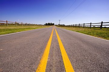 Fototapeta premium A long road bordered by farm fences and telephone wire