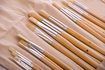 A set of artist paint brushes on canvas carrying case