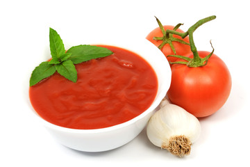 Bowl of tomato soup with two tomatoes and garlic