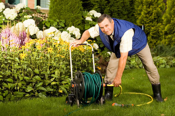 Senior man crimping hose in the garden