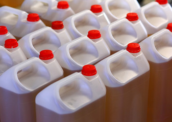 Rows of industrial plastic cans with red caps filled with oil