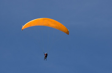 parapente orange sur ciel bleu