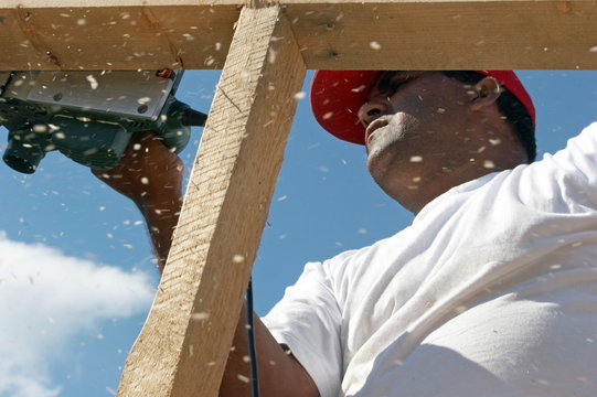 Worker polishing wood frame on top house