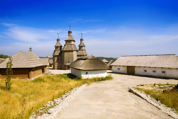 Fototapeta premium Wooden church and huts. Ancient slavic architecture.