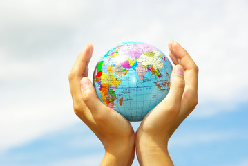 Hand holdings a globe on a sky