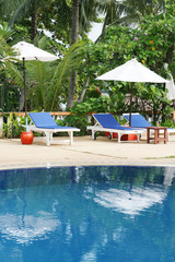 Obraz premium Deck chairs and umbrellas next to a swimming pool.
