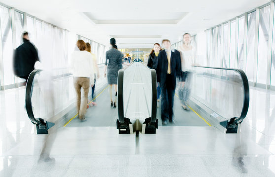 People moving on an escalator through a glass and metal passag