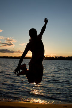 Young Man Jump Over Sunlight Near The River