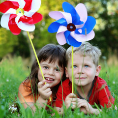 Kids laying on a grass with colorfull pinwheels