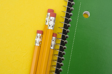Pencils with scribbler on yellow background, day of school