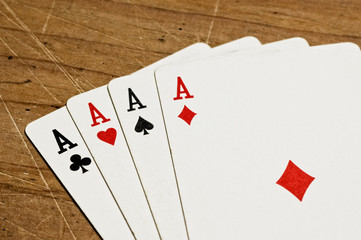 Four aces over an old wooden table, close up.