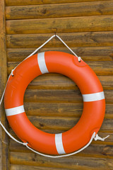 A bright orange lifebuoy hanging on a wooden wall.