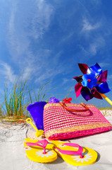 Pretty array of beach accessories on sand dune under blue sky