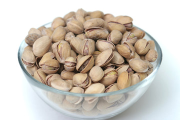 It is a lot of pistachioes in a bowl on a white background