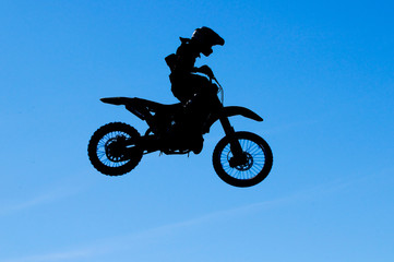 motocross rider making a high jump against a blue sky
